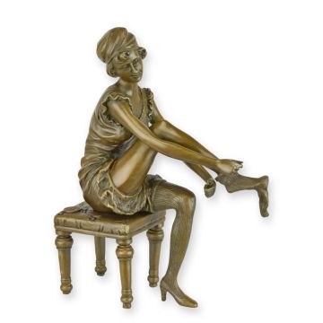 A BRONZE SCULPTURE OF A WOMAN PUTTING ON HER SOCKS