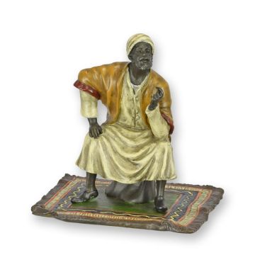 A BRONZE SCULPTURE OF AN ORIENTAL MERCHANT ON CARPET