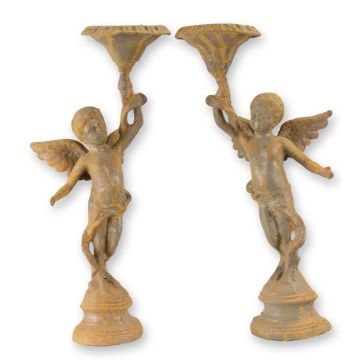 A PAIR OF RUSTY CAST IRON PUTTI CANDLESTANDS