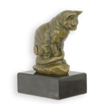 A BRONZE SCULPTURE OF A CAT LOOKING DOWN ON A MARBLE BASE