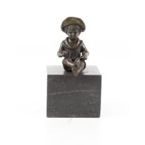EEN BRONZEN ZITTENDE JONGEN OP EEN GROTE MARMEREN SOKKEL